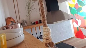 Eine Küche mit einer Holzausziehtheke, einem aufgehängten Geschirrtuch und einer farbenfrohen Wanddekoration.