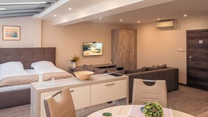 Una moderna camera d'albergo con un letto, una scrivania con una sedia, un divano, una TV e un armadio in legno.