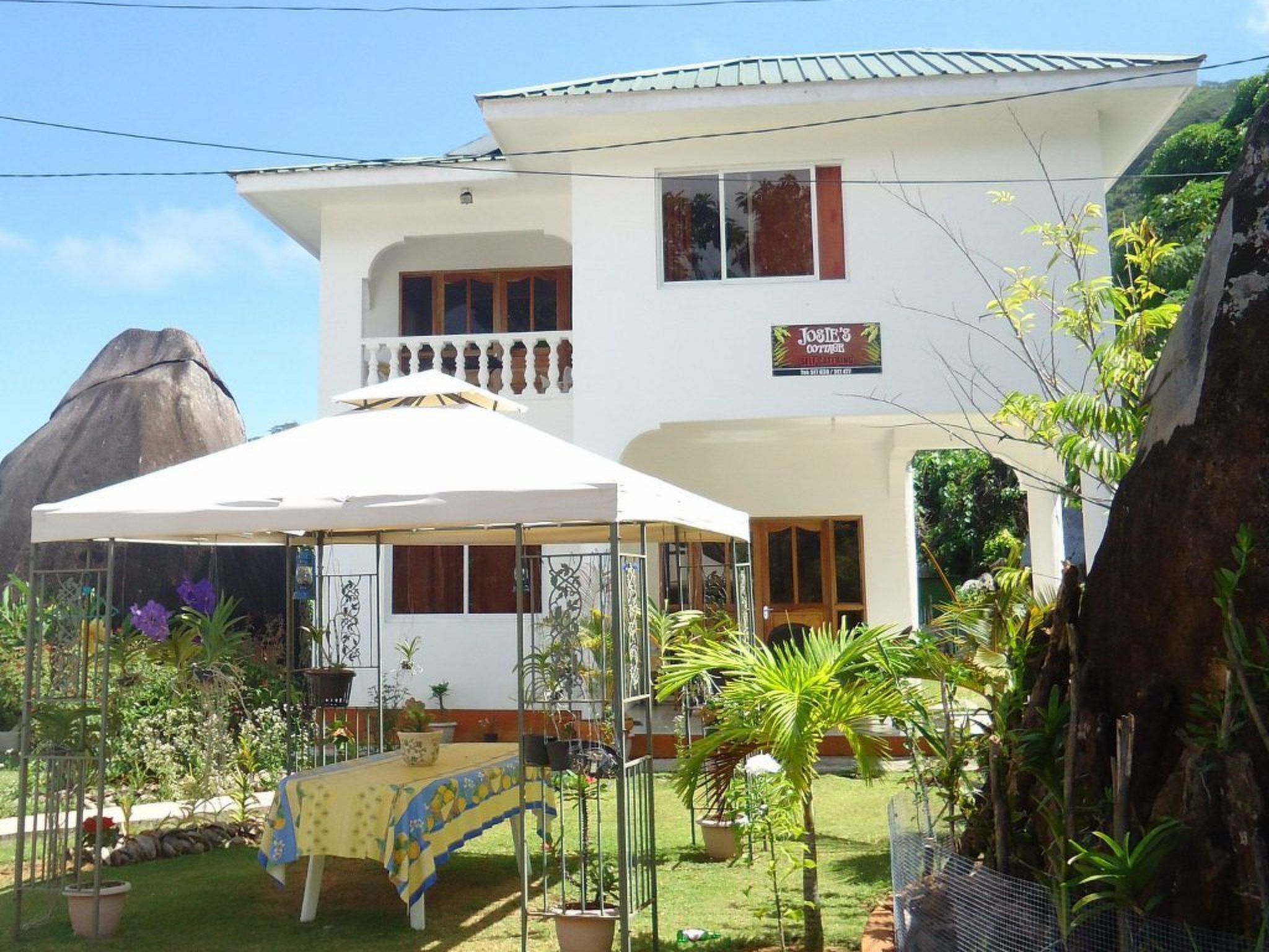 Un bâtiment à deux étages doté d’un balcon, d’un espace extérieur couvert aménagé en coin salon et d’une enseigne indiquant « Josie’s Cottages ».