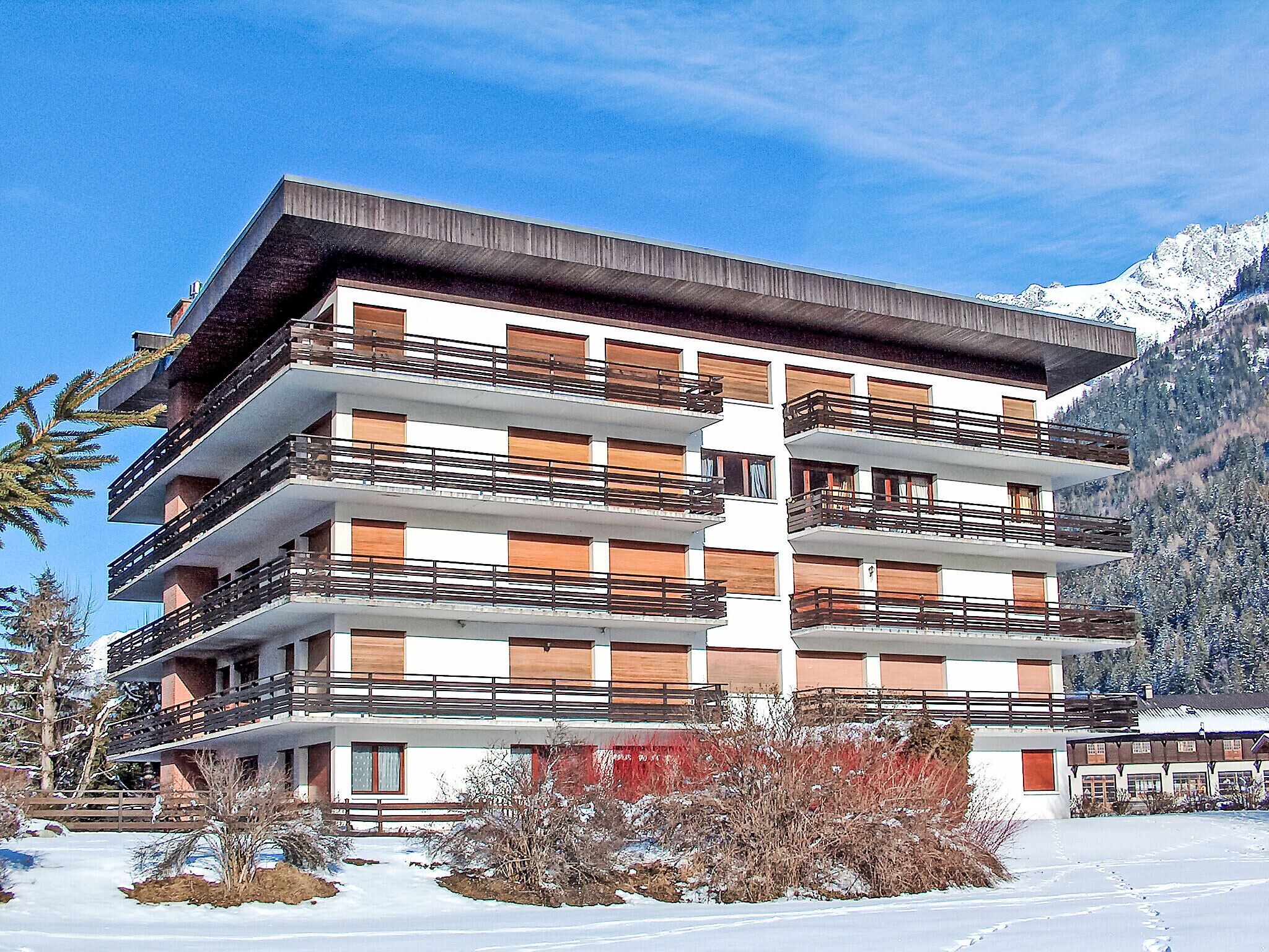 Ett hotell med flera våningar och balkonger, beläget med en snötäckt bergskedja som bakgrund.
