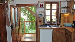 Une cuisine compacte avec une porte en bois, un petit réfrigérateur, une cuisinière à gaz et un évier.