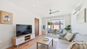 Ein modernes Wohnzimmer mit Flachbildfernseher, Couchtisch aus Holz und einer Couch.