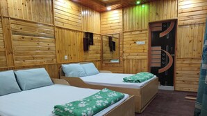 A wooden cabin with two single beds, each with a pillow and a green floral bedspread. - Toru Nibas Eco Resort Saint Martin (Cox's Bazar)