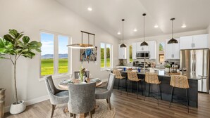 A modern kitchen with white cabinets, a central island with bar stools, and pendant lighting. - Farmland Flat - Bozeman (Bozeman)