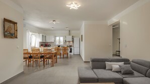 A modern living room with a grey sectional sofa, wooden dining table, and chairs. - Villa Berton – Heated Saltwater Pool (Sveta Nedelja)