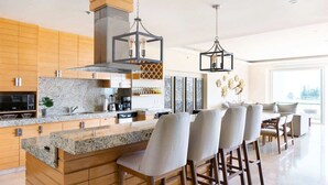 A modern kitchen with granite countertops, wooden cabinets, and a bar area with bar stools.