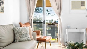 Ein modernes Wohnzimmer mit einer Couch, einem Sessel, einem kleinen Tisch und Blick durch eine Glastür ins Freie.