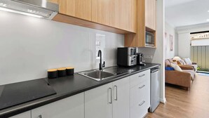 Eine moderne Küche mit Edelstahlgeräten, einer schwarzen Arbeitsplatte und Holzschränken.