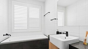 Ein modernes Badezimmer mit Badewanne, Waschbecken und einem großen Spiegel.