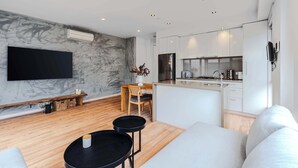 A modern living room with a flat-screen TV, a dining area with a wooden table and chairs, and a kitchen with white cabinets and a stainless steel refrigerator. - Stylish 1BR Unit in Balaclava- Ideal business trip (Balaclava)
