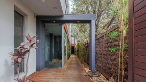 A narrow pathway leading to a modern building with glass doors and a wooden deck. - Stylish 1BR Unit in Balaclava- Ideal business trip (Balaclava)