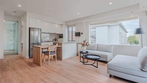 A modern apartment with a kitchen, dining area, and living room. It features a large window, a sofa, and a coffee table. - Stylish 1BR Unit in Balaclava- Ideal business trip (Balaclava)