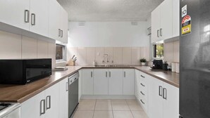 A modern kitchen with white cabinets, a black microwave, and a stainless steel refrigerator. - North Adelaide View | 3BR & Free Parking (North Adelaide)