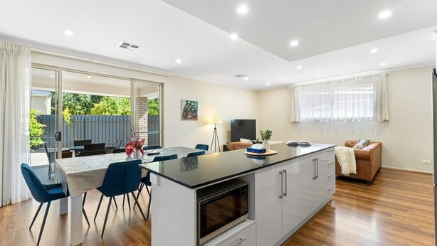 Een moderne keuken met een centraal eiland, een eetgedeelte met stoelen en een televisie.