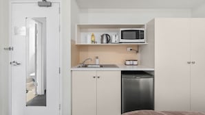 A compact kitchenette with a microwave, sink, and dishwasher.
