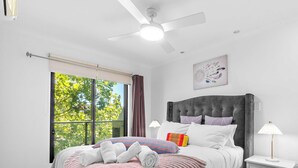 A bedroom with a bed, a ceiling fan, a window with curtains, a bedside lamp, and a wall-mounted artwork. - Cozy 2BR Apt CBD Wi-Fi Free Parking (Adelaide)
