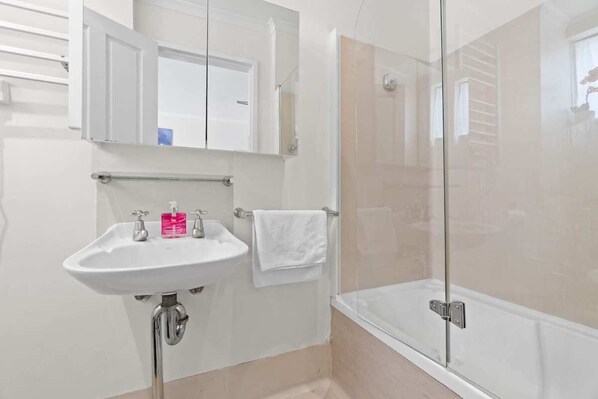 A bathroom with a white sink, a mirror, and a glass-enclosed shower.