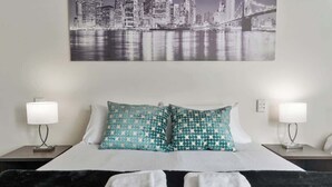 A hotel room with a bed, two nightstands, a cityscape painting, and a black and white patterned blanket. - 1BR Apt in Gourge Chinatown CBD Free WiFi (Adelaide)