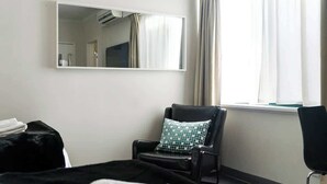 A hotel room with a bed, a chair, a large mirror, and a window with curtains. - 1BR Apt in Gourge Chinatown CBD Free WiFi (Adelaide)