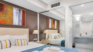 Een moderne hotelkamer met een groot bed, een badkamer met spiegel en kunstwerken aan de wanden.
