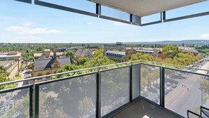 Ein Balkon mit Blick auf eine Stadtlandschaft, einschließlich Gebäude und Grünflächen.