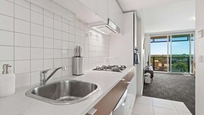 Eine moderne Küche mit Spüle aus Edelstahl, einem Gaskochfeld und einem großen Fenster mit Blick auf die Stadt.