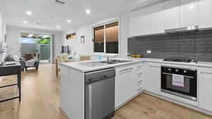 Una cucina moderna con mobili bianchi, lavastoviglie, fornello e un'ampia finestra.