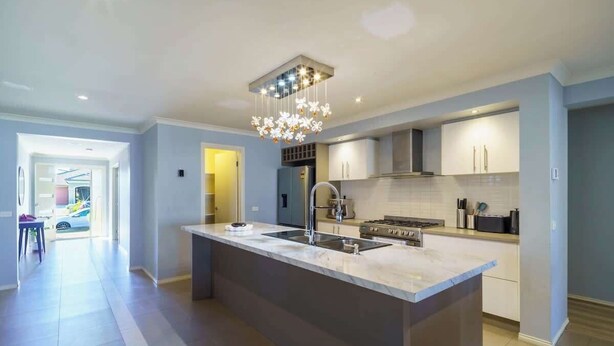 Una cocina moderna con una isla grande, electrodomésticos de acero inoxidable y una araña.