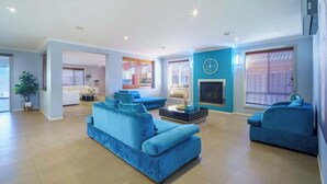 Un salón amplio con un gran sofá azul, una chimenea y un área de comedor visible a través de un arco.