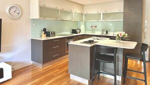 Une cuisine moderne avec un îlot central, un plancher en bois et une horloge au mur.