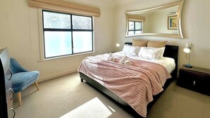 Une chambre à coucher avec un lit, un ventilateur de plafond, une fenêtre, une chaise et une table de chevet.