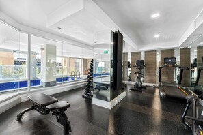 A modern gym with exercise equipment, a bench, and a view of the outside. - Modern City Escape Pool | 2BR Apartment (Adelaide)