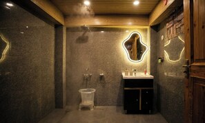 Een moderne badkamer met een stenen muur, een houten plafond, een wastafel met spiegel en een toilet.