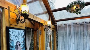 Ein Zimmer aus Holz mit Glasdecke, einem gerahmten Bild an der Wand und einem kleinen Tisch mit Hocker.