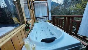 Ein Whirlpool auf einer Holzterrasse mit Blick auf eine Berglandschaft.