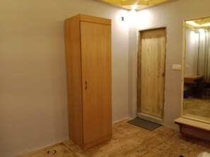 Ein Zimmer mit einem Holzschrank, einer Tür, einem Spiegel und einer Fußmatte.