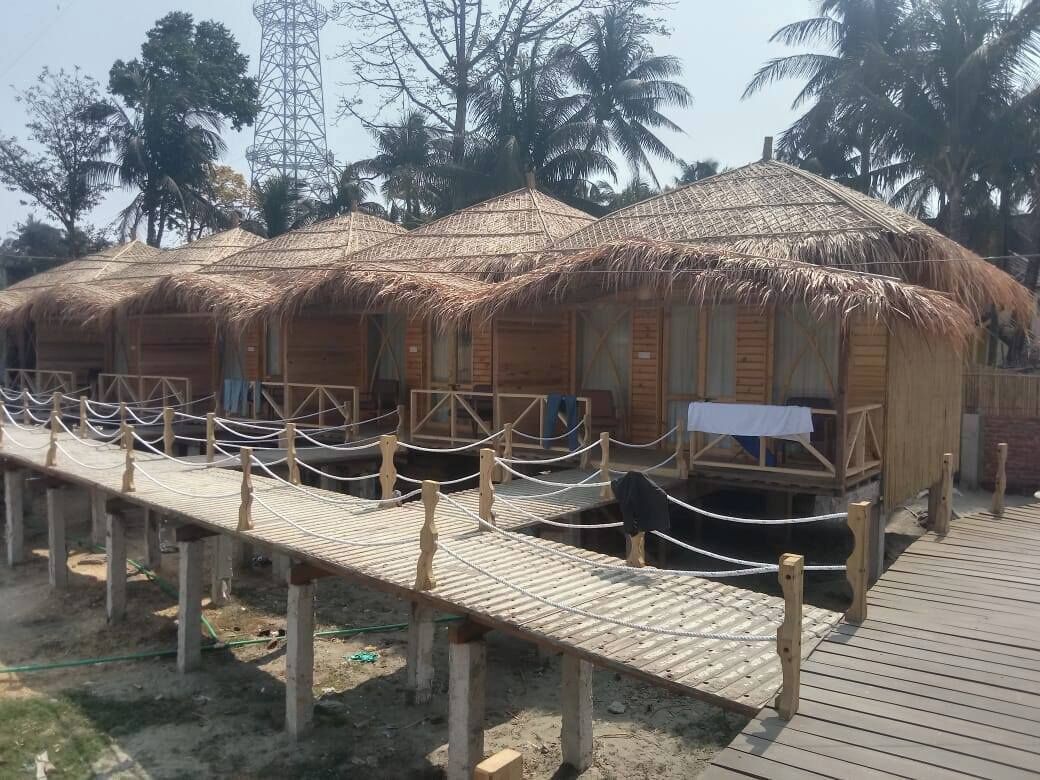 A row of thatched-roof huts with wooden railings and a wooden walkway.
