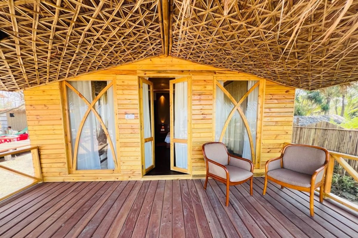 Eine Holzhütte mit einem Strohdach, zwei Stühlen und einer Holzterrasse.
