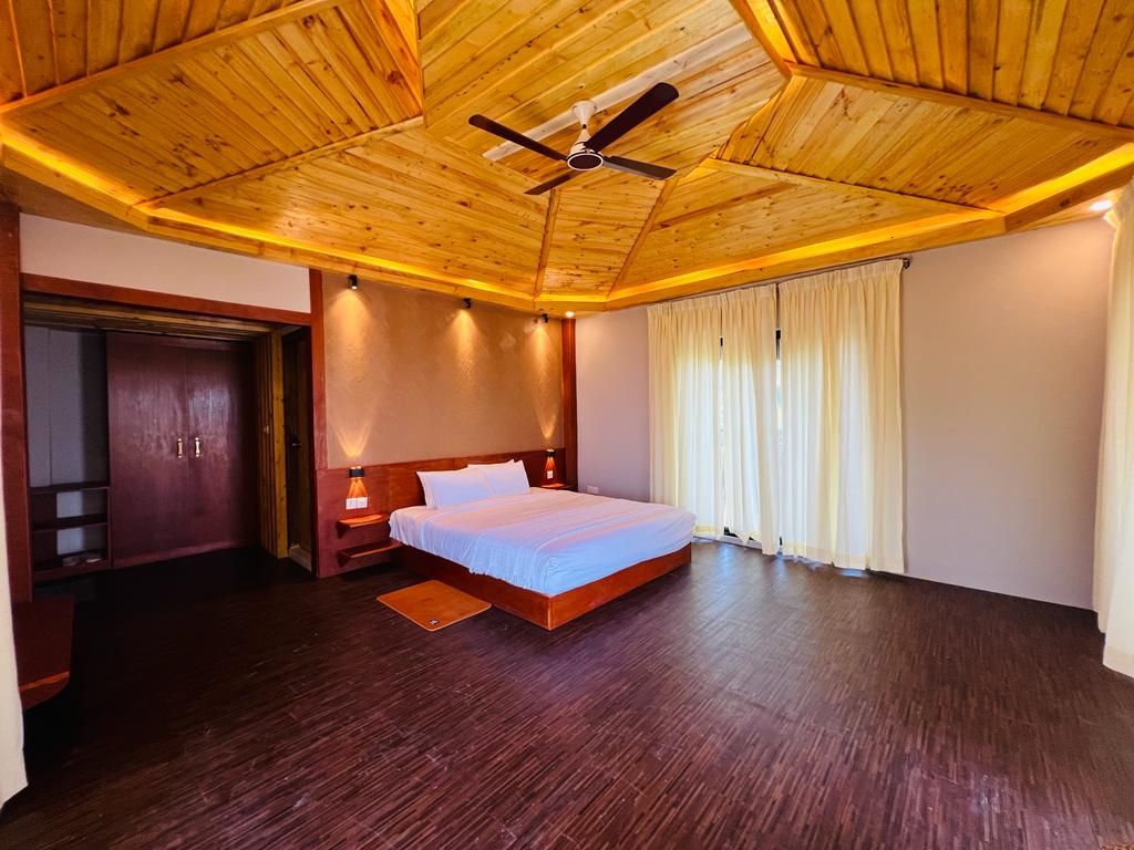 Un dormitorio con techo de madera, una cama, una mesita de noche y un armario.