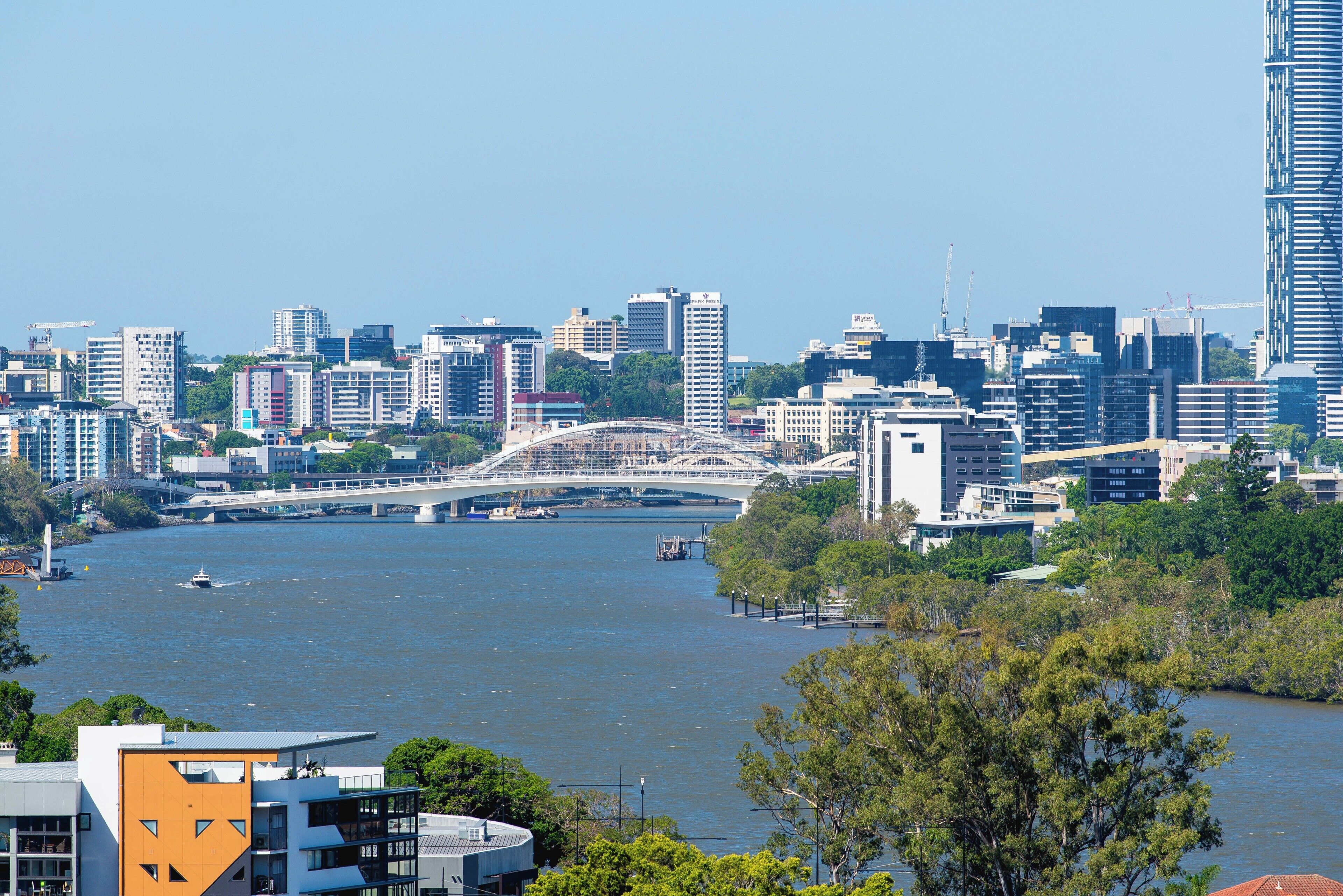 A cityscape with a river, modern buildings, and a bridge.