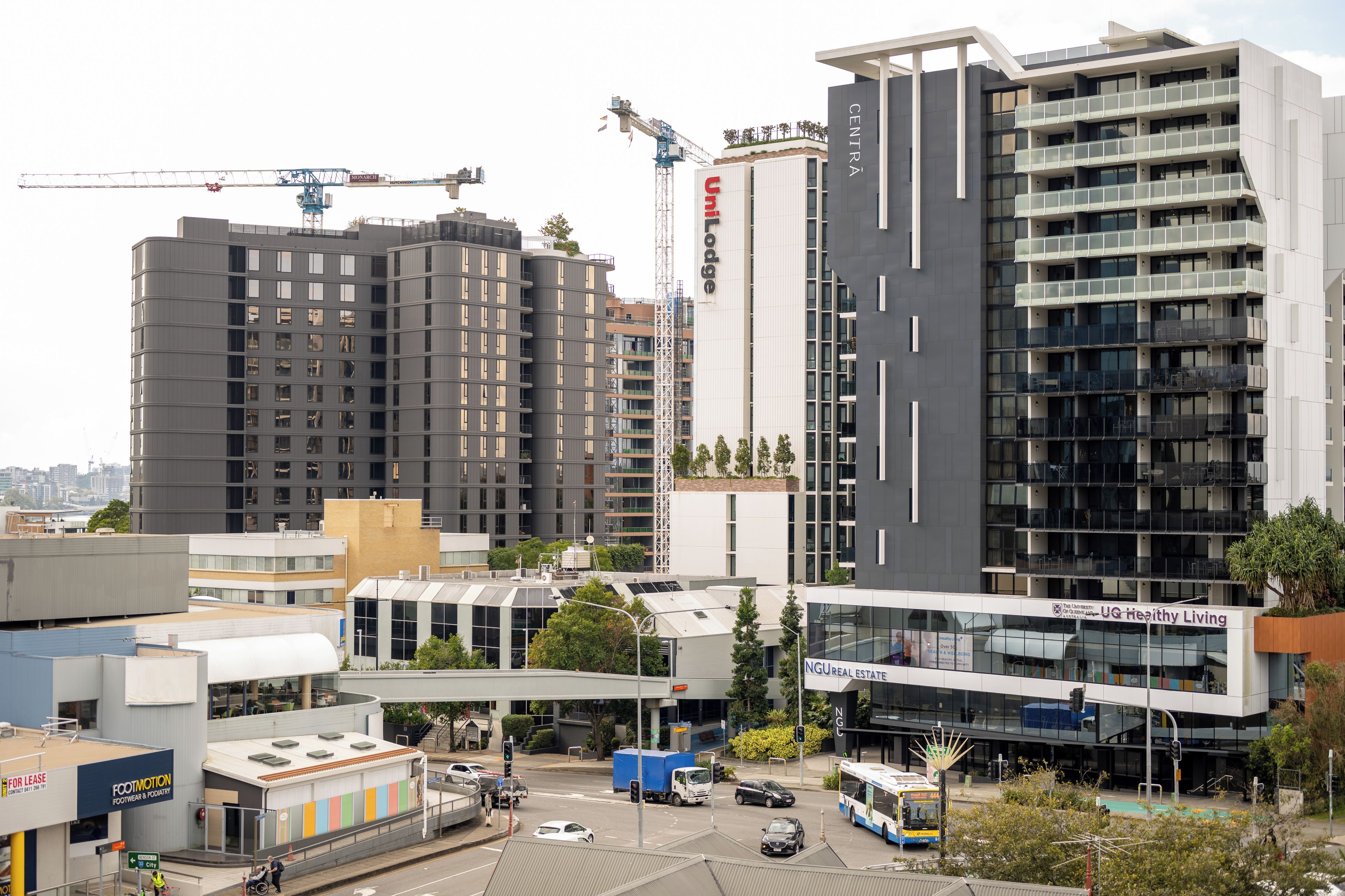 Un moderno edificio de rascacielos con varios balcones y una grúa de construcción al fondo.