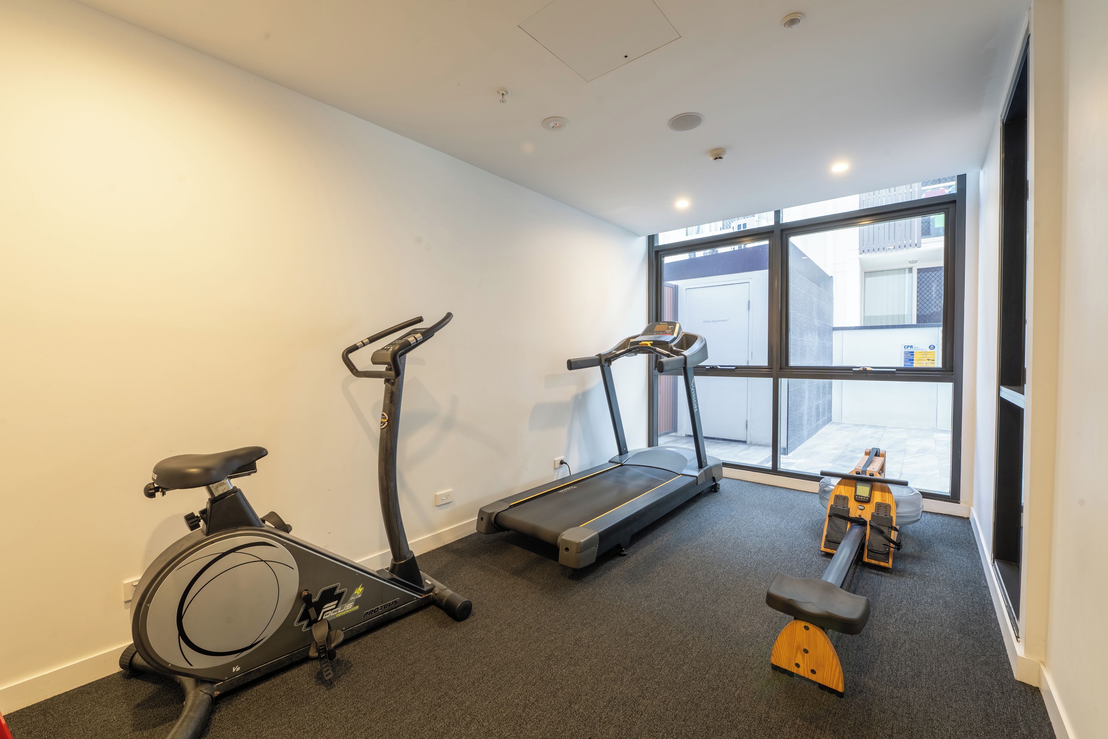 A gym with a stationary bike, treadmill, and rowing machine.