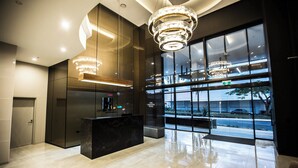 A modern lobby with a marble reception desk, large windows offering a view of the street, and contemporary lighting fixtures. - High Street Apartments Toowong (brisbane)