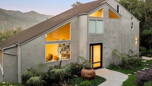 A modern house with a sloped roof, large windows, and a well-maintained garden.