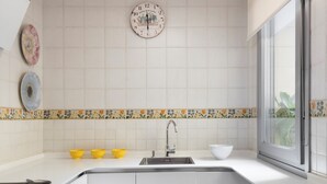 Eine moderne Küche mit weißen Schränken, einer zentralen Kochinsel, einem Spülbecken und einem Fenster.