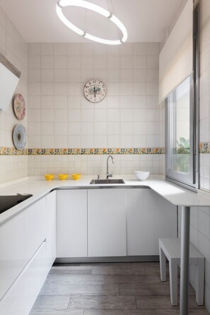 Een moderne keuken met witte kasten, een centraal eiland, een spoelbak en een raam.
