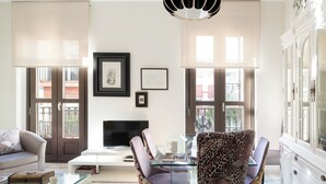 Ein modernes Wohnzimmer mit einem Glastisch, einer Couch, einem Sessel mit Leopardenmuster und einem weißen Schrank.