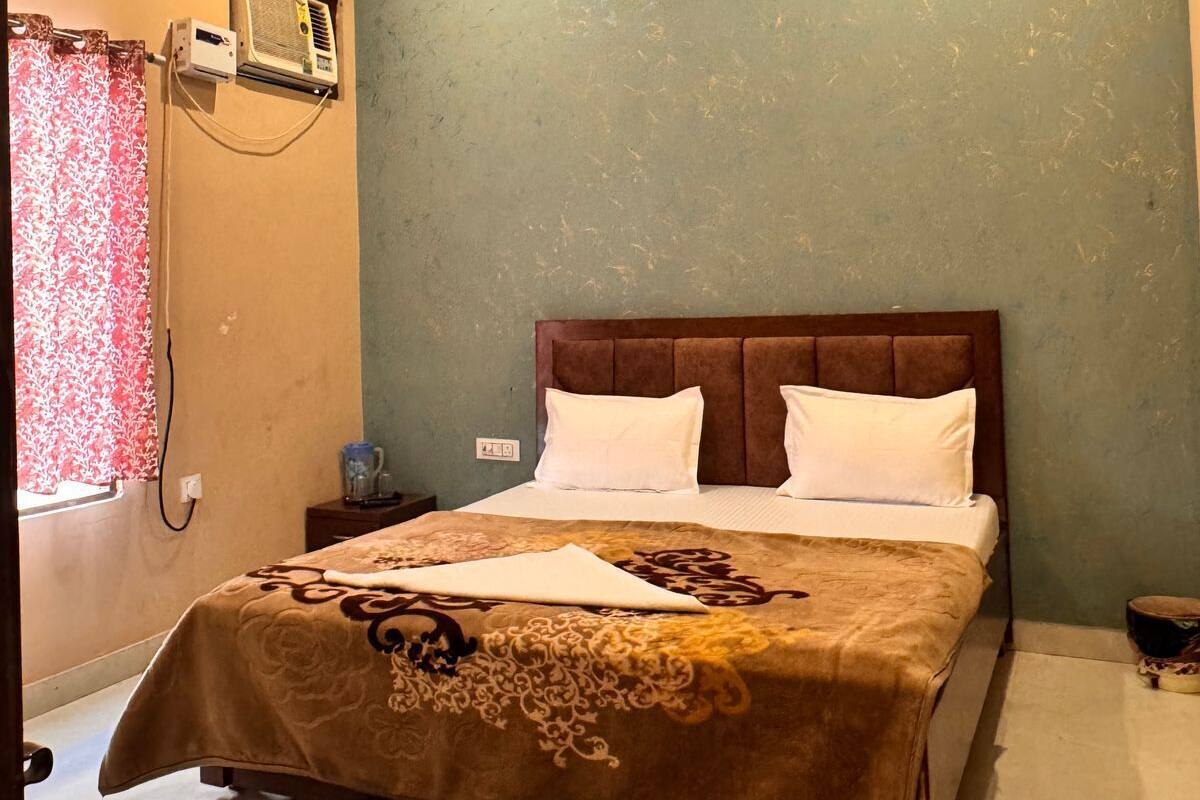 A bedroom with a bed, a ceiling fan, a window with curtains, and an air conditioning unit.