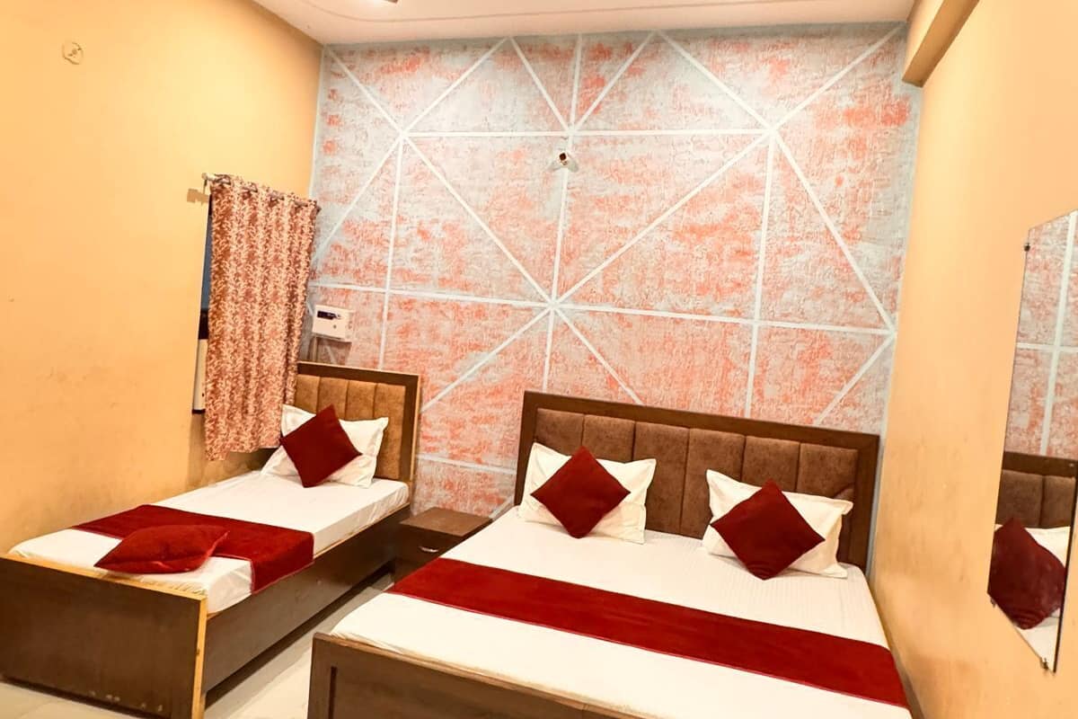 A hotel room with two single beds, a ceiling fan, and a patterned wall.