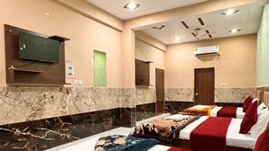 A hotel room with a marble wall, a ceiling fan, a flat-screen TV, and a minibar. - Hotel Raghav Dham (Vrindavan)